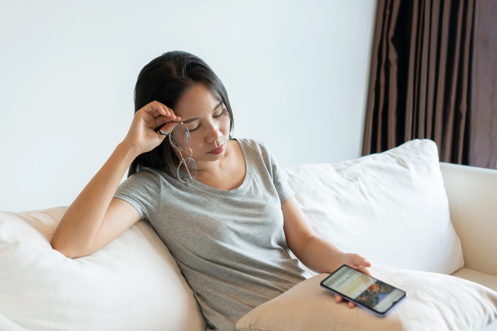 tired young asian woman taking off glasses feeling eyestrain using mobile phone home businesswoman suffering from dry eye syndrome fatigue after long cellphone use