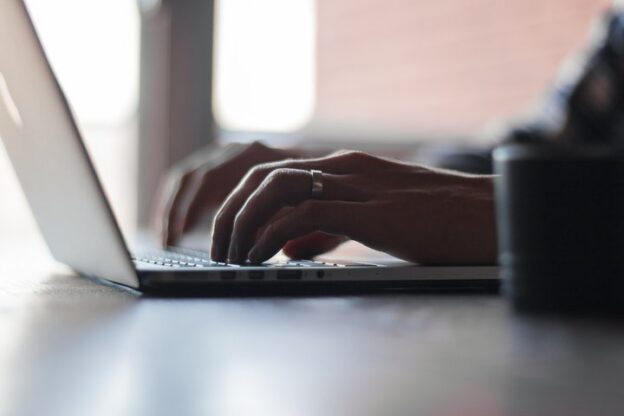 Hands typing on a laptop keyboard during a website update